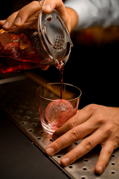 从带有过滤器的调酒杯中倒入鸡尾酒的过程的特写镜头图片下载