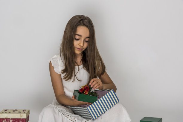 快乐的小女孩手里拿着礼品盒在白色的背景上图片下载