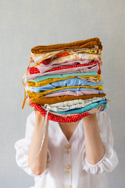 一个欧洲女人手里拿着很多彩色的衣服，准备送去洗衣店或回收利用图片下载