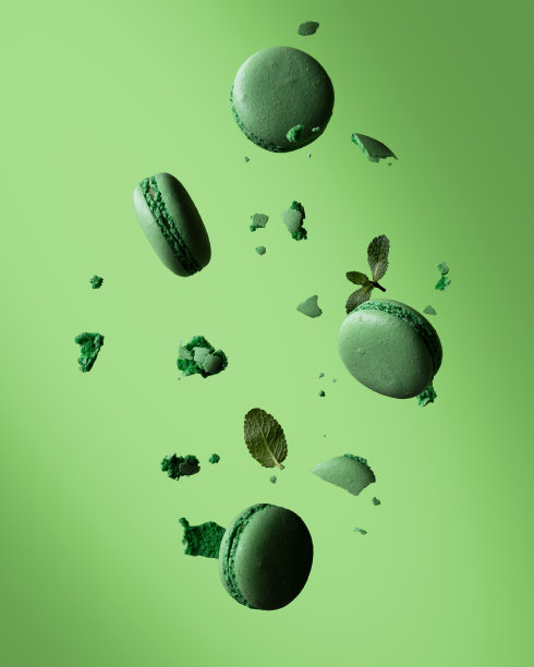 法国绿色蛋白杏仁饼在绿色背景上飞舞。食物和甜点漂浮在空中。图片下载