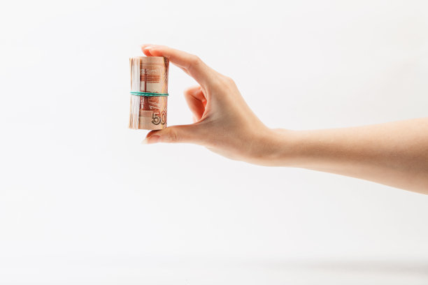 一位女性的手握着一卷钱。侧视图,特写。白色背景。副本的空间。世界反腐败日概念，12月9日图片下载