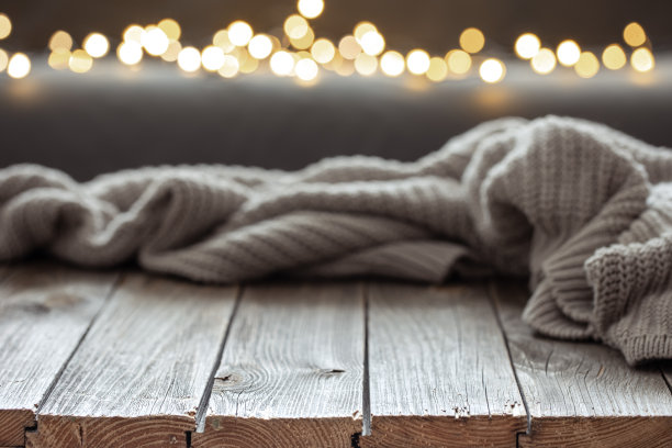 舒适的背景与针织元素在木制表面和散景灯。图片下载
