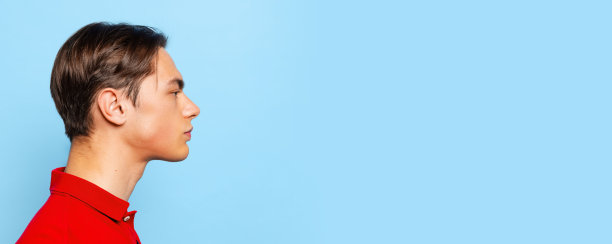 年轻英俊的男子的侧面视图，学生看着直孤立在蓝色工作室背景。摩天观景轮图片下载