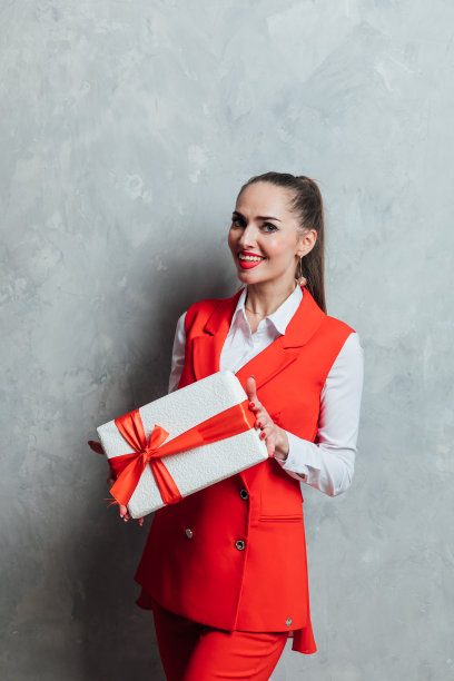 美丽的女人带着红色的礼物在圣诞树前新年图片下载