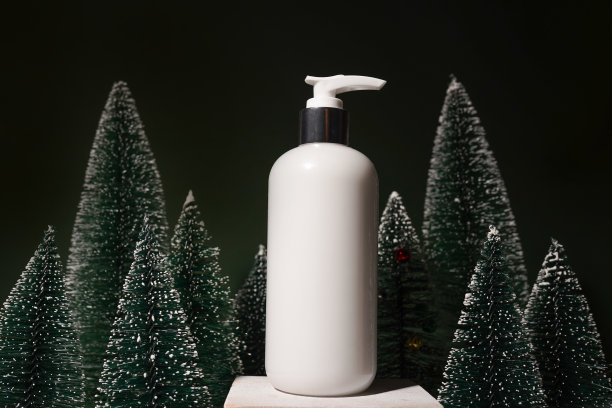 化妆产品，沐浴露或沐浴露在绿色圣诞背景和杉树上。冬季身体护理产品图片下载