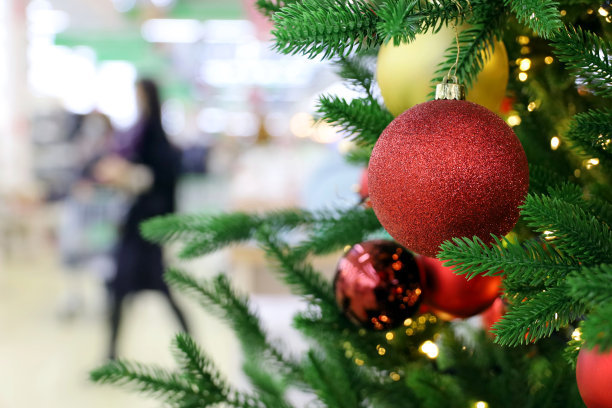 圣诞大甩卖，购物中心的新年圣诞树上挂着玩具球，背景是人图片下载