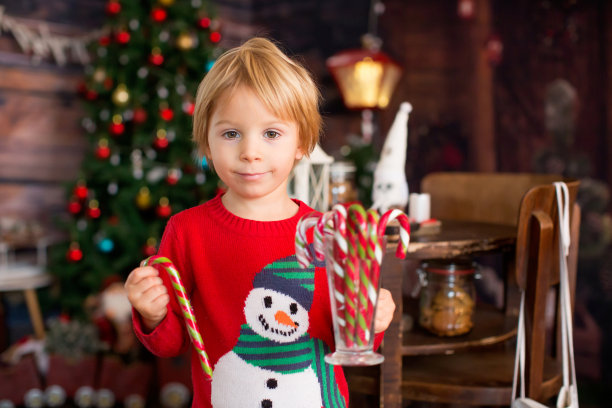 金发小孩，蹒跚学步的男孩，圣诞节在家玩得很开心，看书，玩拐杖糖图片下载