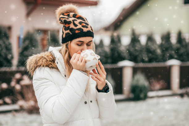 年轻女子在雪地花园喝咖啡图片下载