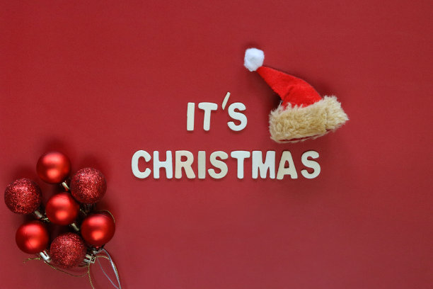 自制DIY简单的圣诞贺卡设计的图像，红色背景上剪出白色字母，手工制作的节日圣诞贺卡，这是圣诞讯息与圣诞老人的帽子和红色的小玩意，复制空间图片下载