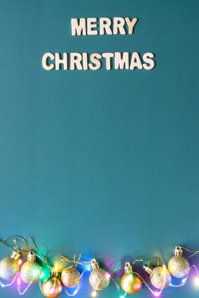 自制DIY简单的圣诞卡设计的图像，在蓝绿色的背景上剪出白色字母，手工制作的节日圣诞贺卡，圣诞快乐的信息与金色的小玩意和发光的仙女灯，复制空间图片下载