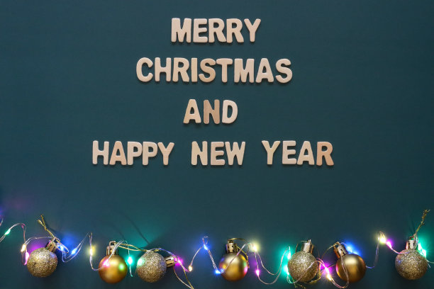 自制自制简易圣诞贺卡的图像，蓝绿色背景上剪出白色字母，手工制作的圣诞贺卡，圣诞快乐和新年快乐的信息，金色的小玩意和彩灯图片下载