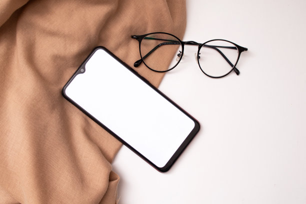 手机和眼镜在布上白色的背景图片下载