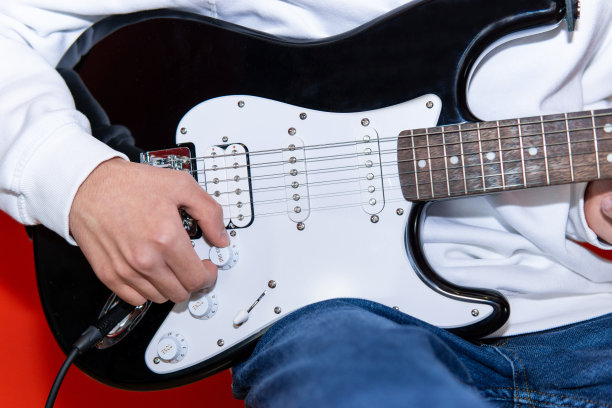 一个年轻人调整电吉他音量的特写。音乐、乐器教育、娱乐、摇滚明星、音乐会及学习理念图片下载