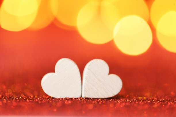 情人节：爱心符号，金色散景红色背景上的两颗白色爱心图片下载