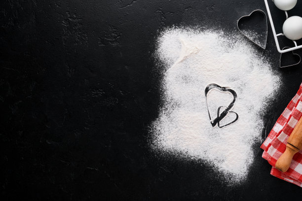 情人节烘烤背景与心脏形状，面粉，工具和配料自制饼干在黑色的桌子上。爱装饰食品背景。横幅。前视图。图片下载