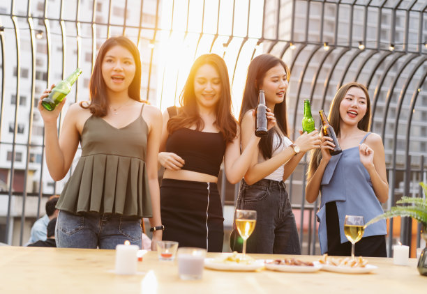 亚洲女孩团伙喝啤酒，同时享受屋顶酒吧派对。一群朋友在露天派对上玩得很开心。关于女人狂欢夜的概念。图片下载