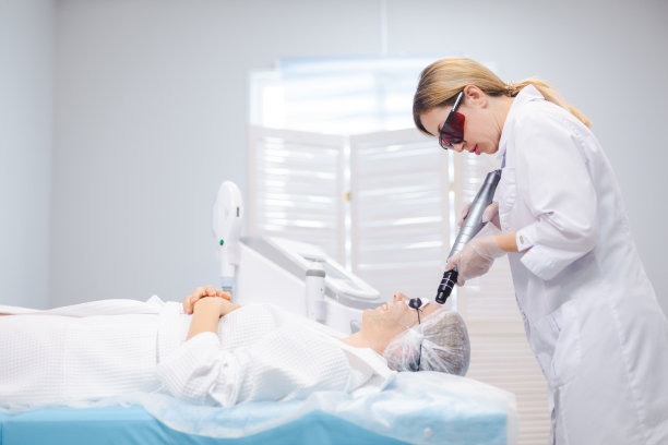 一个年轻女孩戴着防护眼镜在美容院进行碳剥离手术时的侧面照片图片下载