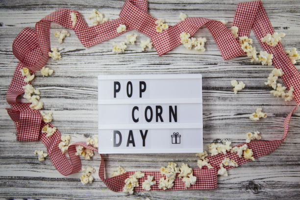 灯箱与文本爆米花日之间的爆米花和节日红丝带背景。前视图。复古风格图片下载