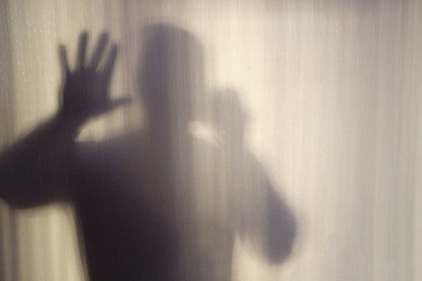鬼影子。恐怖的影子。把手放在玻璃上。人的影子。磨砂玻璃后面的危险人物。万圣节的背景。模糊的照片图片下载