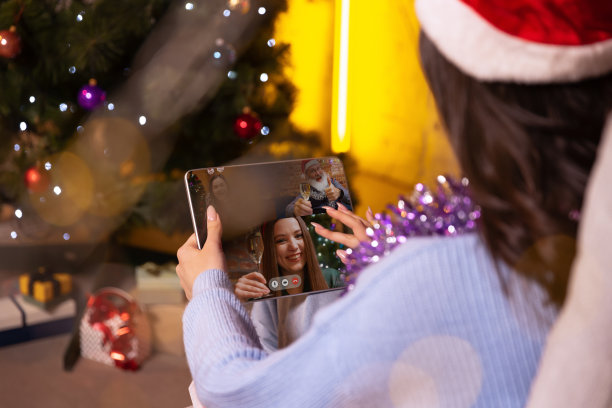 年轻女孩使用平板电脑的后视镜，通过视频通话的方式与朋友交谈。圣诞装饰品回家。图片下载