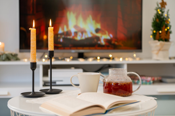 在舒适的家边桌上茶壶，书和蜡烛与壁炉的背景图片下载