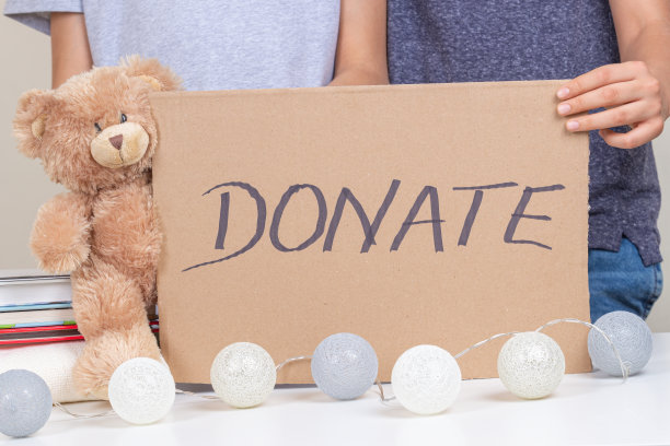 志愿者手持棕色纸板，上面写着“捐赠”。孩子们为孩子们收集衣服、书籍和玩具。圣诞节捐款，节日慈善理念图片下载