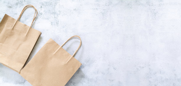 再生纸购物袋与绿色树叶在棕色的背景。零废物，无塑料概念。环保，可持续的生活方式图片下载
