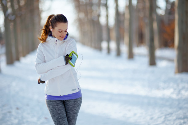 穿着白色夹克，戴着耳机，面带微笑的健身女士图片下载