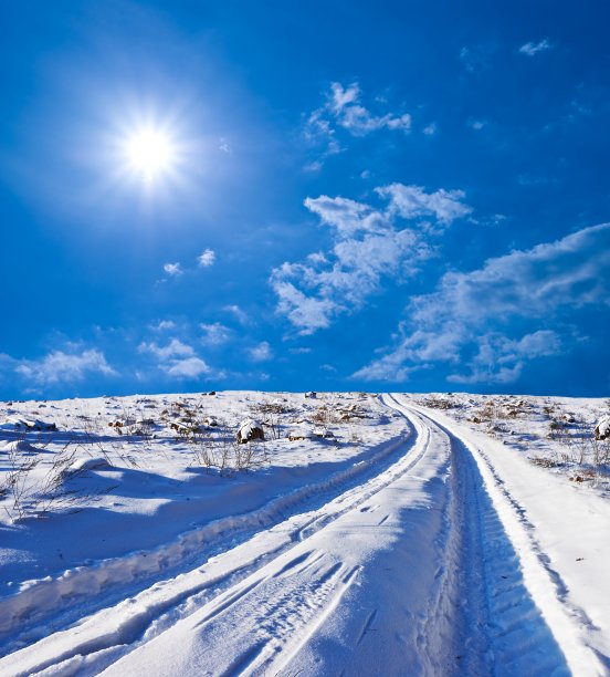 道路在冬天被雪封的平原上由一个阳光灿烂的日子图片下载