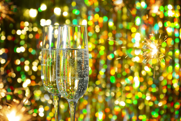 喜迎新年象征。明亮的抽象背景与香槟眼镜，玩具和烟花在黑暗的背景图片下载