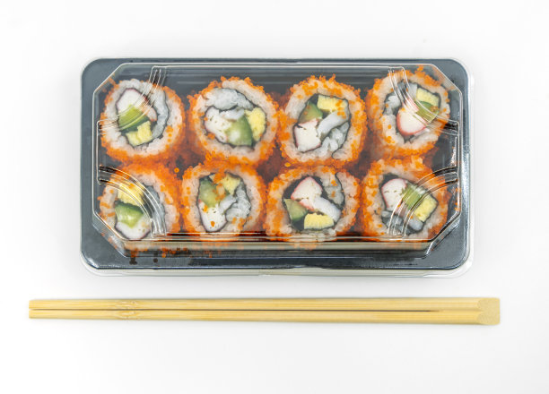 俯视图寿司卷准备吃在塑料容器与筷子，孤立的图像在白色背景。图片下载