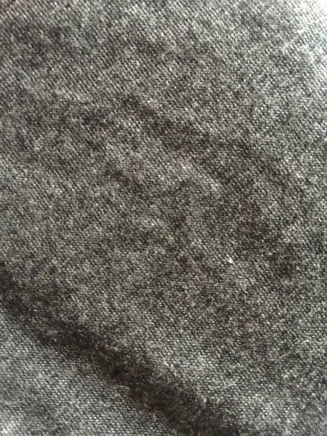 接近的深灰色布表面的背景与毛茸茸的表面纹理。图片下载