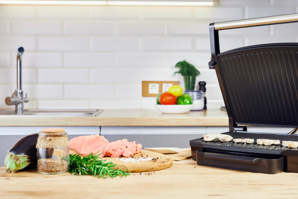 厨房内部正在准备烧烤。厨房的餐桌上有电烤架和烤肉。图片下载