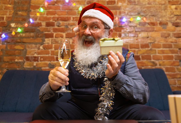 情绪激动的大胡子老人坐在家里，通过视频电话和朋友家人一起庆祝新年。图片下载