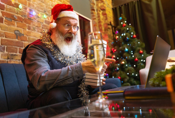 情绪激动的大胡子老人坐在家里，通过视频电话和朋友家人一起庆祝新年。图片下载
