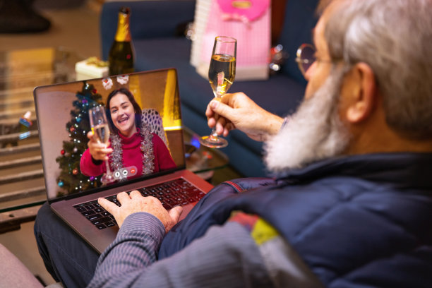 快乐的大胡子老头坐在家里，通过视频电话和女儿家人一起庆祝生日。图片下载