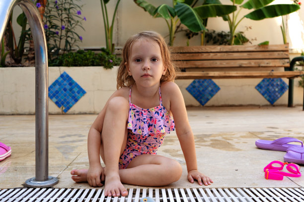 可爱的小女孩穿着泳装坐在游泳池附近图片下载