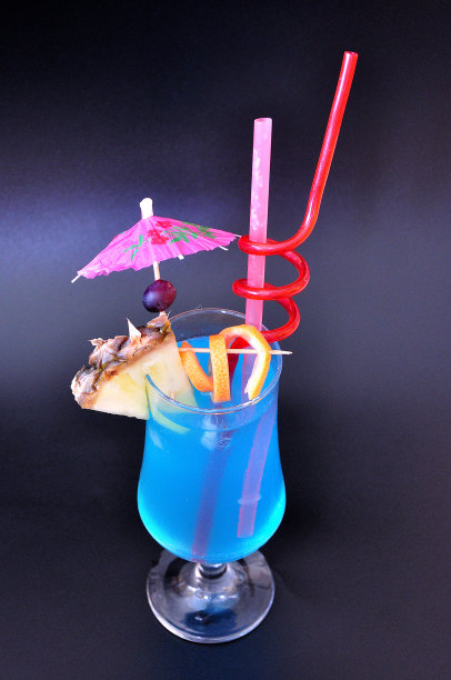 蓝色泻湖，高杯沙滩鸡尾酒，黑色背景，加冰和一片菠萝。图片下载