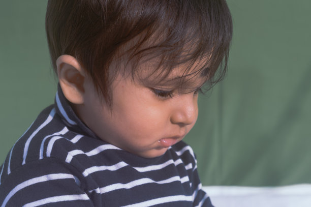 美丽可爱的悲伤的婴儿在下巴下的姿势。无聊的脸，孤独的男孩低下头陷入沉思，心烦，不高兴和悲伤。关闭了。印度的种族。头像照片。孤立的背景图片下载