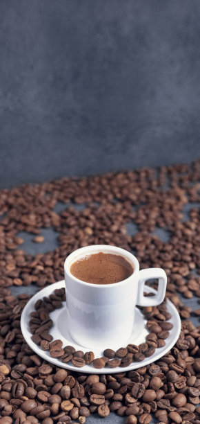 白色杯子里的土耳其咖啡。旁边有个咖啡研磨机。地上有咖啡豆。灰色背景，土耳其文化，咖啡因，咖啡杯。图片下载