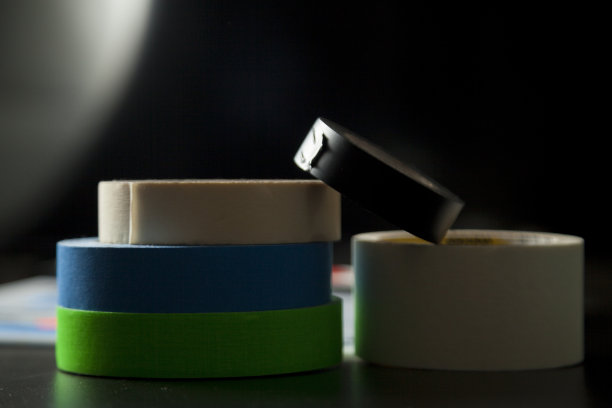 彩色胶带堆放在桌子上和黑色背景。图片下载