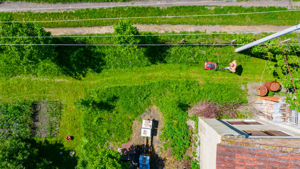 农民用汽油割草机在花园里修剪草坪的鸟瞰图图片下载