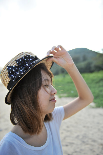 一个年轻女子的侧面照片，在海滩上闭着眼睛微笑。图片下载