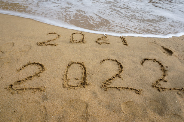 在海滩上，2021这个词被海浪冲走，留下了2022这个词。图片下载