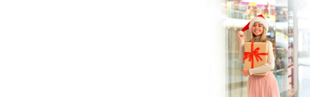 快乐的年轻女子，戴着圣诞帽，拿着礼盒在购物中心。假日购物和礼物。销售。购物中心。副本的空间。横幅图片下载