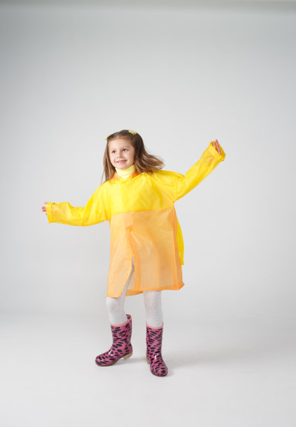 一个穿着黄色雨衣和靴子的小女孩的肖像。孤立在白色背景上。图片下载