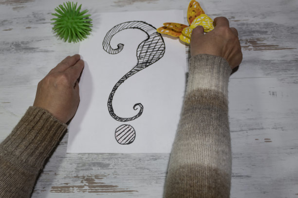 女性的手放在一张带问号的纸旁边图片下载