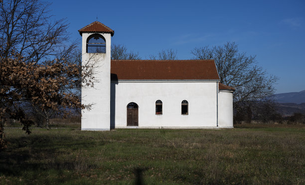 乡村教堂的景色。美丽的教堂院子里有一片巨大的草地，上面是美丽的天空。图片下载