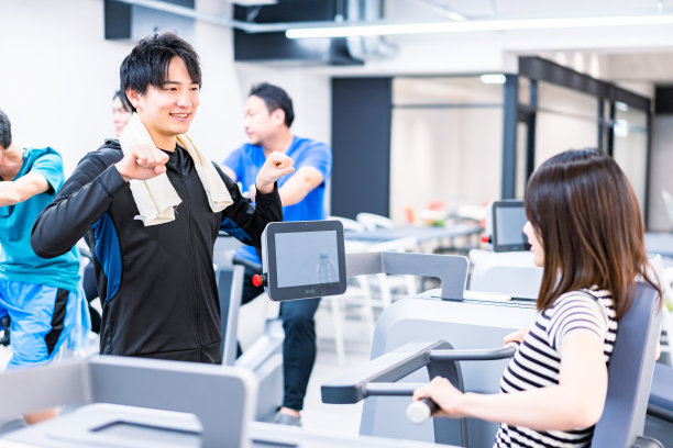 年轻女子在健身房接受教练的指导图片下载