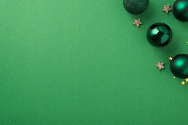 俯视图照片的圣诞装饰在右上角的绿色球，小发光的星星，金星形状的五彩纸屑和闪亮的亮片与copyspace孤立的绿色背景图片下载